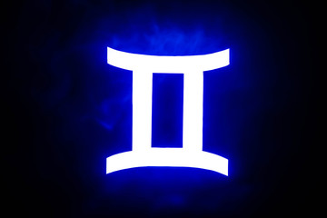 blue illuminated Gemini zodiac sign with colorful smoke on background