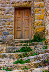Stone walls and stone stairs leading to old weatherd door in Deir El Qamar