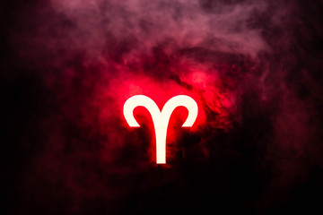red illuminated Aries zodiac sign with smoke on background