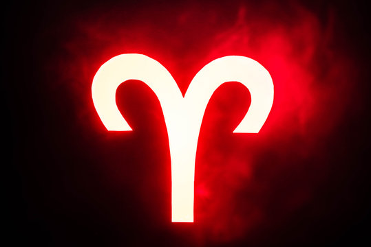 Red illuminated Aries zodiac sign with smoke on background