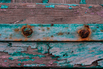 Metal hinge and rusty screws on a weathered door with fading paint