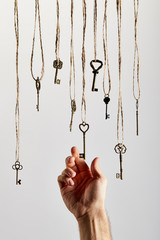 Fototapeta na wymiar cropped view of man touching vintage keys hanging on ropes isolated on white