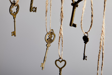 Fototapeta na wymiar close up view of vintage keys hanging on ropes isolated on grey