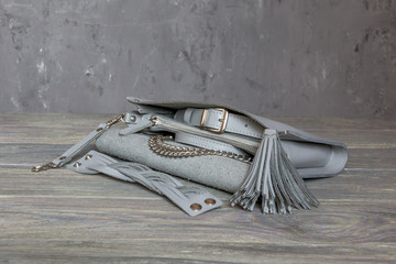 Grey, leather elegant women handbag with bracelet, shoulder strap on grey background. Horizontal orientation