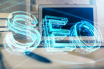 Multi exposure of table with computer and seo drawing hologram. Search optimization concept.