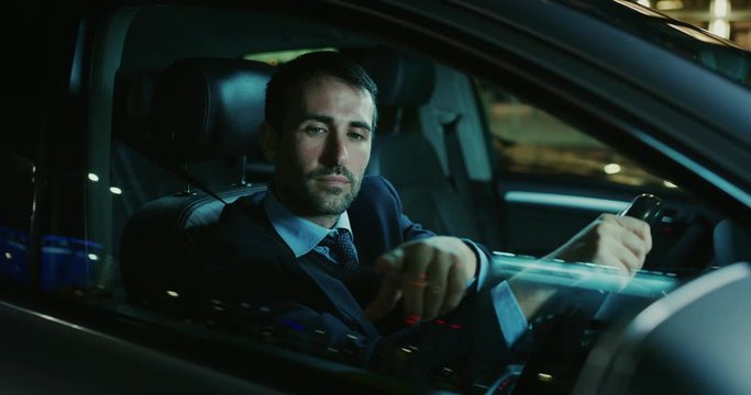 A handsome businessman is using an application of self pilot on a futuristic screen with augmented reality holograms  before a drive a car.