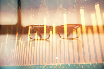 Financial graph hologram with glasses on the table background. Concept of business. Double exposure.