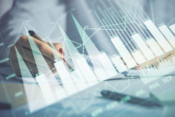 Double exposure of woman's hands making notes with forex graph hologram. Concept stock market analysis.