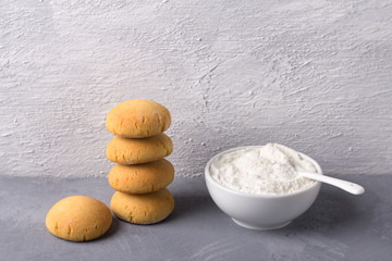 Homemade gluten free cottage cheese rice cookies and bowl rice flour on on gray textured...