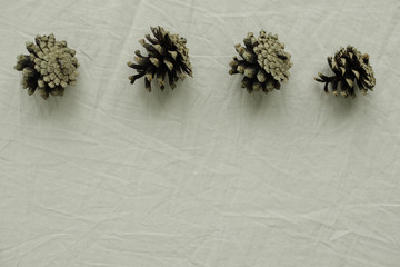 Natural minimalist background with four pine cones at beige crumpled textile. Eco scandinavian lifestyle.