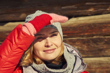 winter portrait of an attractive woman in a hat and scarf in wooden background.