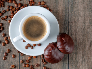 Cup of coffee and coffee beans with chocolate marshmallows for breakfast on a wooden background. Photo for background. View from above.