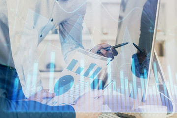 Double exposure of chart with businessman typing on computer in office on background. Concept of...