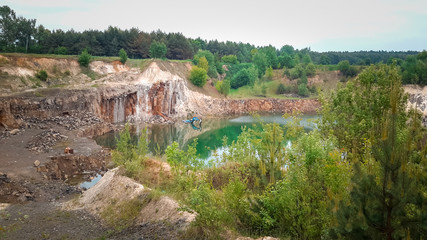 flooded quarry with water and an abandoned excavator