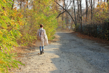 Fototapeta premium Young woman walking outdoors. Full length portrait of teenage girl walking in the forest, back view.