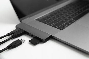 Laptop with USB Type-C adapter with pluged USB cables and SD card. The USB adapter under the Type-C...