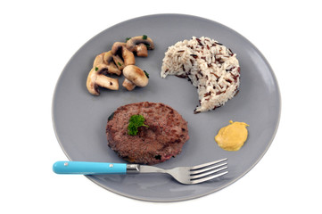 Steak haché avec du riz et des champignons dans une assiette