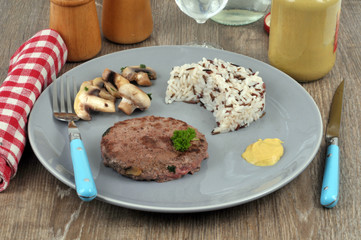 Steak haché avec du riz et des champignons dans une assiette