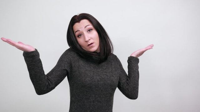 Beautiful caucasian young woman in fashion black sweater spreads hands, looking unhappy over isolated white background, Lifestyle concept