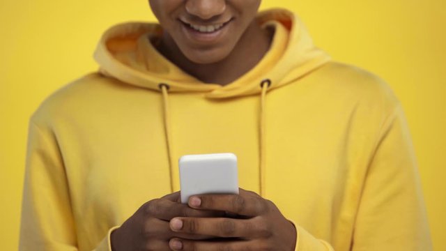 cropped view of african american teenager using smartphone isolated on yellow