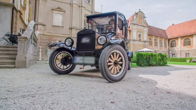 Chauffeur driving a beautiful old timer car in front of a stunning wedding location.