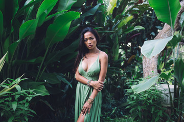 Seductive Asian woman standing in tropical garden