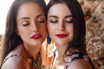 The young beautiful woman with tan on the beach, near the rocks