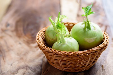 Fresh kohlrabi in basket on wooden background