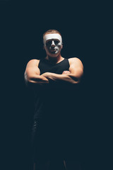 Athlete bodybuilder on a dark background. Dramatic portrait. The masked man.