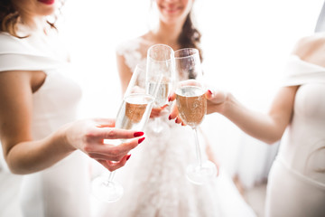 Photo bride with her friends drinking champagne from glasses