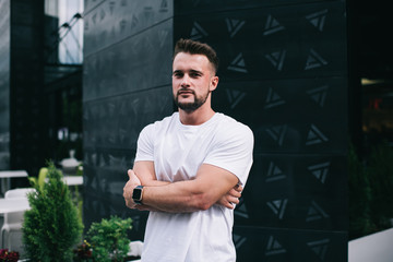 Confident young man standing against building in street