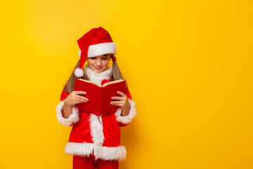 Little girl wearing Santa costume reading a book