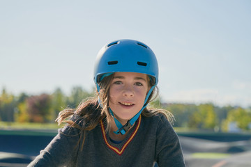 Smiling girl with blue safety bicycle helmet and background of urban landscape and nature