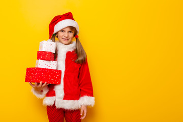 Little girl in Santa costume holding pile of Christmas presents