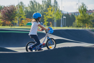The bike lane for children. Children have fun on the race track. A child in a blue helmet riding a bicycle for safety