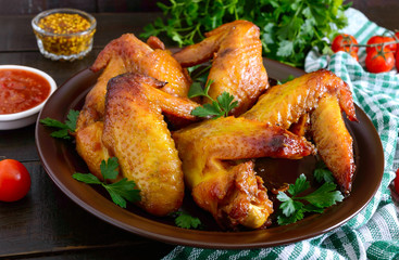 Baked chicken teriyaki wings in honey mustard sauce with adjika and mustard on dark wooden table.  Asian recipe. Rustic style