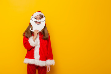 Child in Santa costume holding cardboard beard