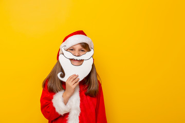 Fototapeta premium Little girl dressed as Santa holding cardboard beard