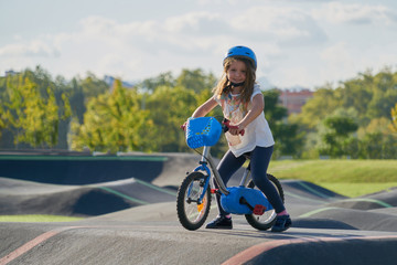 The bike lane for children. Children have fun on the race pump track. A child in a blue helmet riding a bicycle for safety