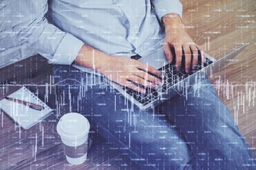 Double exposure of businessman's hands with laptop and stock market graph background. Concept of research and trading.