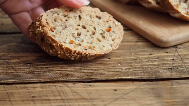 A man spreads cream cheese on a piece of grain bread. Wooden background Close up.