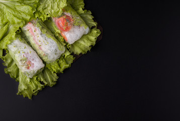 spring rolls in rice paper on a black background with place for text