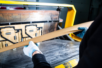 Man putting carton into a punching machine. Cardboard boxes production. Paper die cutting machine.