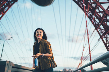 Portrait of cheerful carefree asian hipster girl having fun travelling with roaming connection,smiling young woman looking at camera holding mobile phone resting on city urban architecture background