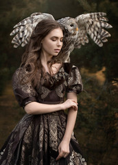 Tender and sensual art photo of a girl with an owl, spreading wings