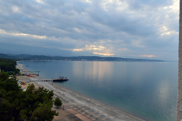 Pebble beach of the black sea at sunset behind the clouds