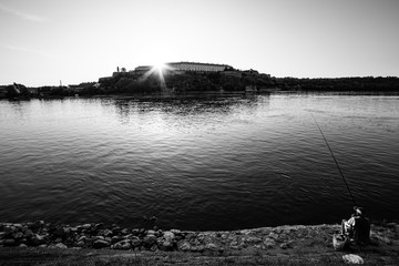 Novi Sad, Serbia August 10, 2019: Petrovaradin fortress in Novi Sad. Novi Sad and Danube river at sunrise.  Fisherman on the bank of the Danube river
