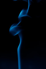 Obraz premium Silhouette of a woman from the smoke of incense sticks trendy classic blue on a dark background.