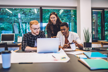 Multicultural millennials analyzing websites analytic during remote work in coworking space with...