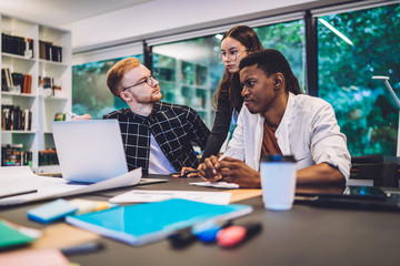 Skilled youth reading received email during distance working near desktop with modern laptop technology connecting to 4g wireless in coworking space, millennials browsing websites for e learning